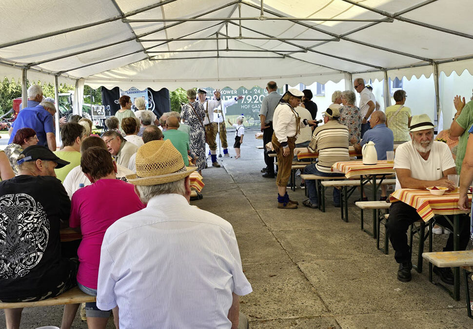 Gäste des Erntefestes in Wilsickow sitzen in einem Festzelt an Tischen und unterhalten sich angeregt.